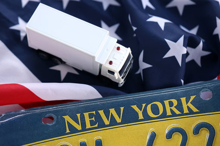 Toy truck and USA state of New York license plate on US flag. Concept of driving in New York....