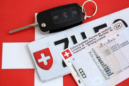 Switzerland car license plate and ignition key on Swiss flag close up. Driving permit and registration conceptの写真素材