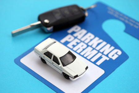 Parking permit paper notice tag for car interior with ignition keys and toy car. Parking permit for people with disabilities conceptの写真素材