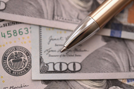 One hundred US dollar bills and silver pen close up. Concept of business calculating and accounting...