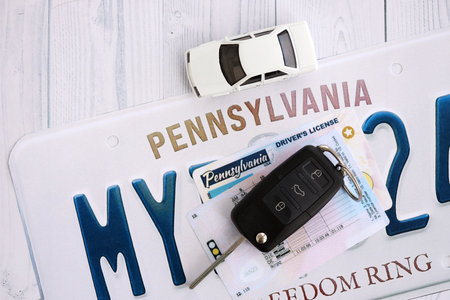 Remote control car keys on Pennsylvania license plate with driver license. Concept of driving in Pennsylvania. Reaching a driving permitの写真素材