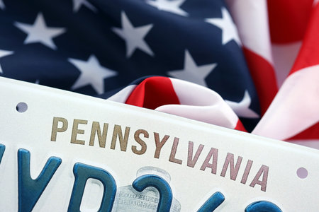 USA state of Pennsylvania license plate on US flag. Concept of driving in Pennsylvania. Reaching a driving permitの写真素材