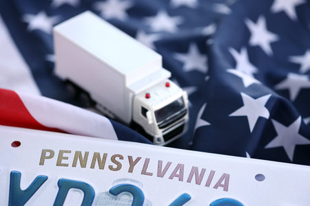 Toy truck and USA state of Pennsylvania license plate on US flag. Concept of driving in Pennsylvania. Reaching a driving permitの写真素材
