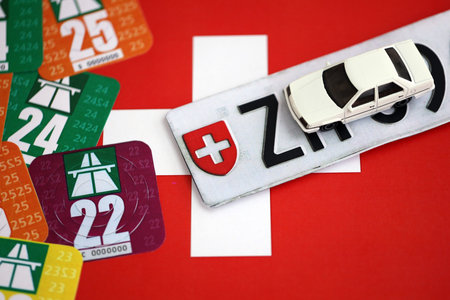 Switzerland vignette stickers for different years with toy car on Swiss flag close up. Driving permit and registration conceptの写真素材