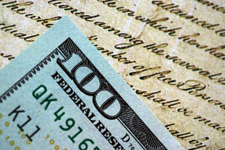 One hundred US dollar bills and United States Constitution page fragment. Concept of lawsuit in...