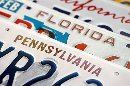 Old US car license plates with various state names close up. Concept of driving in United States. Reaching a car registrationの写真素材