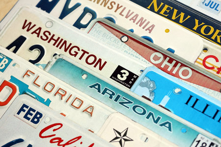 Old US car license plates with various state names. Concept of driving in United States. Reaching a car registrationの写真素材