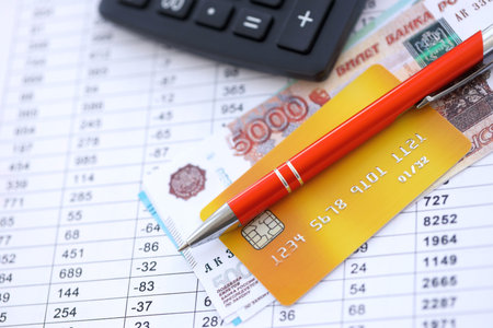 Credit card and pen with russian ruble currency money bills banknotes on calculations document background. Business, financial operations and accounting in Russian Federationの写真素材