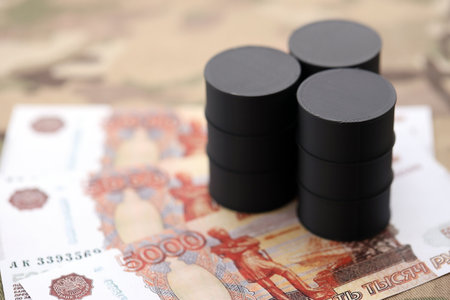 Three oil barrels on russian roubles money bills on camouflage fabric. Concept of oil export from Russiaの写真素材