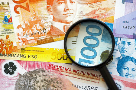 Philippines peso currency money bills and magnifying glass close up. The concept of financial monitoring and taxationの写真素材