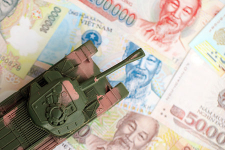 Vietnamese dong currency money bills and toy tank close up. The concept of army funds and weapons salesの写真素材