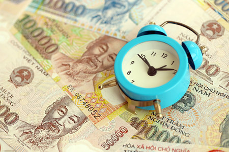 Vietnamese dong currency money bills and alarm clock close up. The concept of time management and incomeの写真素材