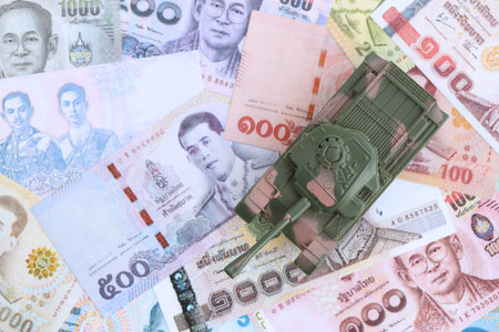 Thai baht currency money bills and toy tank close up. The concept of army funds and weapons salesの写真素材