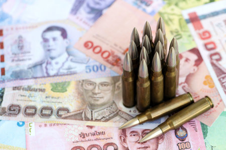 Thai baht currency money bills and rifle bullets close up.の写真素材