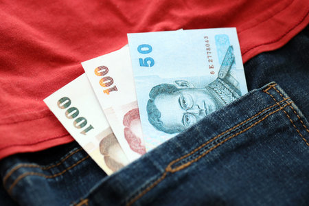 Thai baht money bills in denims pocket close up. The concept of fashion and wealthの写真素材
