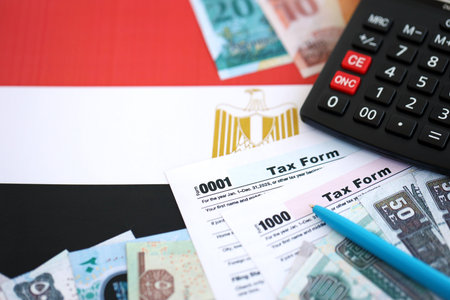 Egyptian pound money bills and calculator with tax form on flag close up. Taxation and accounting conceptの写真素材