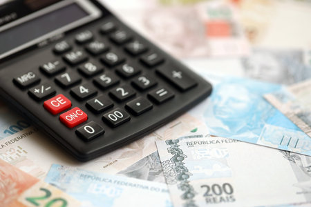 Brazilian reais banknotes and calculator. The current Brazil real money bills and calculator lies on table in big amount. The concept of taxation and money count in Brazilの写真素材