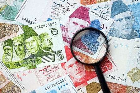 Pakistan rupees banknotes and magnifying glass. The current Pakistan money bills and magnifying glass lies on table in big amount. The concept of financial monitoring and taxation in Pakistanの写真素材