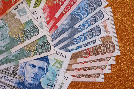 Pakistan rupees banknotes on golden yellow background. The current Pakistan money bills lies on table in big amount. The concept of business and investment in Pakistanの写真素材