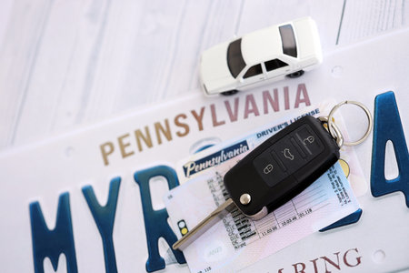 Remote control car keys on Pennsylvania license plate with driver license. Concept of driving in Pennsylvania. Reaching a driving permitの写真素材
