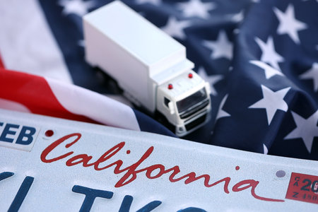 Toy truck and USA state of California license plate on US flag. Concept of driving in California. Reaching a driving permitの写真素材