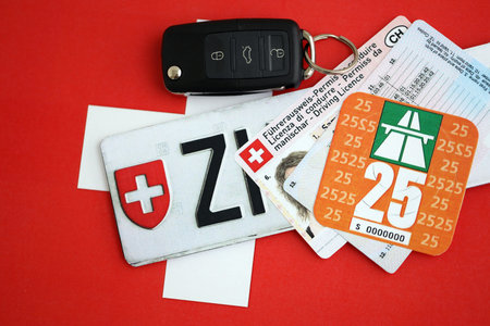 Switzerland vignette sticker for 2025 year and license plate with ignition key on Swiss flag close up. Driving permit and registration conceptの写真素材