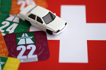 Switzerland vignette stickers for different years with toy car on Swiss flag close up. Driving permit and registration conceptの写真素材