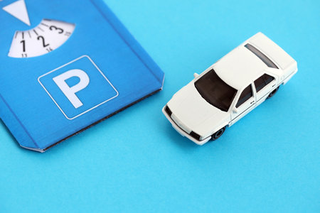 Parking disc for windshield and white toy car. Limited time parking system in european countries. Concept of parking time count in busy parking lotsの写真素材