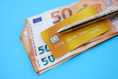 Credit card and pen with euro currency money bills banknotes on light blue background. Business, financial operations and accounting in European Unionの写真素材