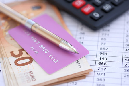 Credit card and pen with euro currency money bills banknotes on calculations document background. Business, financial operations and accounting in European Unionの写真素材