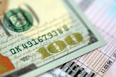 Hundred dollar bill on US driver license close up. Concept of driving lessons or automobile taxpayingの写真素材