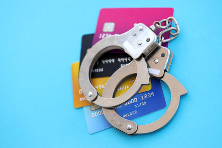 Various credit cards and police handcuffs bracelets on blue background. Concept of banking risks, scam and card skimmingの写真素材
