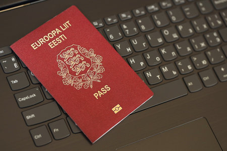 Estonia passport lies on black laptop keyboard buttons background close up. Technologies and control in Europe conceptの写真素材