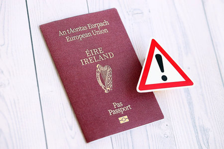 Ireland passport with exclamation sign on white wooden background close up. Problems with citizenship in Europe conceptの写真素材