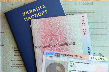 German Permanent resident card and document specimen lies with Ukrainian passport on wooden table close up. Aufenthaltstitel and Fiktionsbescheinigungの写真素材
