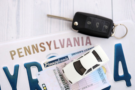 Remote control car keys on Pennsylvania license plate with driver license. Concept of driving in Pennsylvania. Reaching a driving permitの写真素材