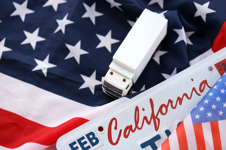 Toy truck and USA state of California license plate on US flag. Concept of driving in California....