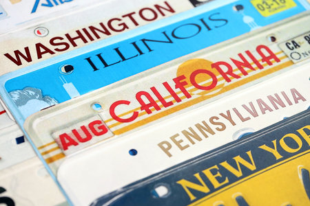 Old US car license plates with various state names. Concept of driving in United States. Reaching a...