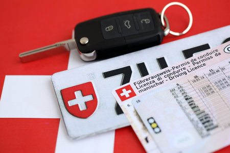 Switzerland car license plate and ignition key on Swiss flag close up. Driving permit and registration conceptの写真素材