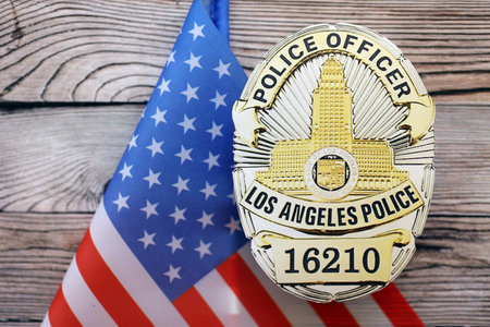KYIV, UKRAINE - SEPTEMBER 17, 2025 US LAPD Police officer badge with flag on wooden table close upのeditorial素材
