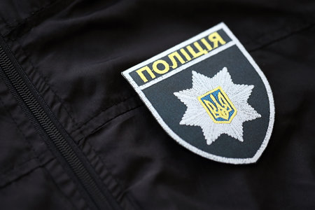 KYIV, UKRAINE - SEPTEMBER 17, 2025 Ukrainian Police badge on black uniform fabric surface close up