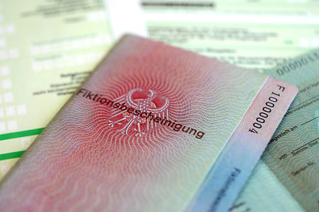 KYIV, UKRAINE - AUGUST 31, 2025 German temporary Permanent resident card specimen lies on german tax form close up. Fiktionsbescheinigung and einkommensteuererklarungのeditorial素材