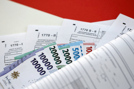 KYIV, UKRAINE - JANUARY 27, 2024 Indonesian tax forms 1770 Individual Income Tax Return and others with money on table close upのeditorial素材