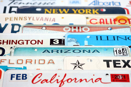 Old US car license plates with various state names. Concept of driving in United States. Reaching a car registration