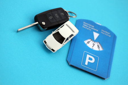 Parking disc for windshield and white toy car with ignition keys. Limited time parking system in european countries. Concept of parking time count in busy parking lotsの写真素材