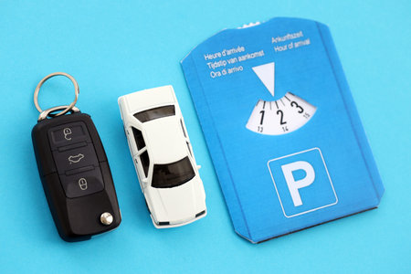Parking disc for windshield and white toy car with ignition keys. Limited time parking system in european countries. Concept of parking time count in busy parking lotsの写真素材
