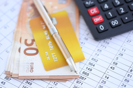 Credit card and pen with euro currency money bills banknotes on calculations document background....