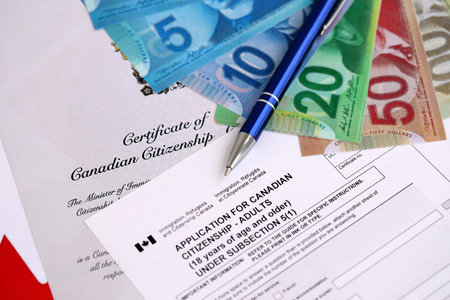 Canadian certificate of citizenship and application with money on Canadian flag close up