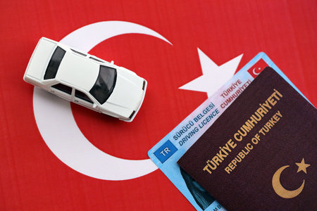 Turkiye driving permit concept. Driver license with passport and toy car on turkish flag close upの写真素材