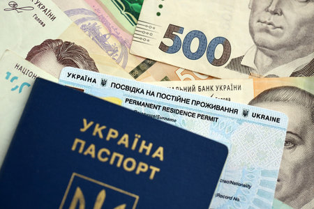 Ukrainian residence permit card or permanent resident card with passport on Ukrainian money close upの写真素材